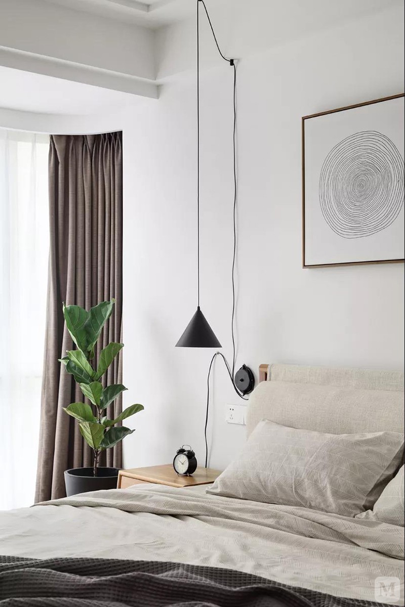 净白的空间氛围，简洁利落的布置所营造的舒适度借由床铺的棉麻质感得到放大。床侧利用床头吊灯的走线融入灵动快活的画面感。床尾斗柜充当简单的绿植端景，再挂上一面圆框镜，营造出别致情调。