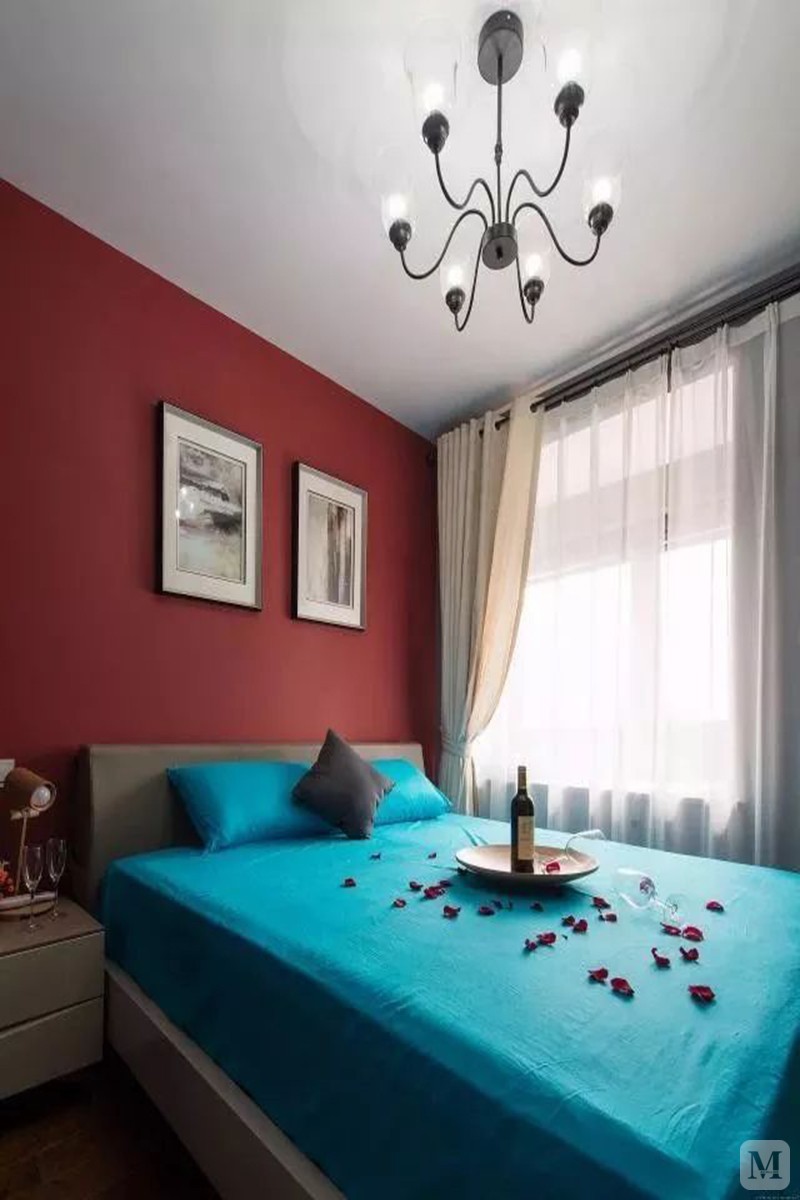 卧室在丹红的床头背景下，搭配一床蓝色的床单，红酒与鲜花洒落，呈现出一个稳重与情趣的空间。